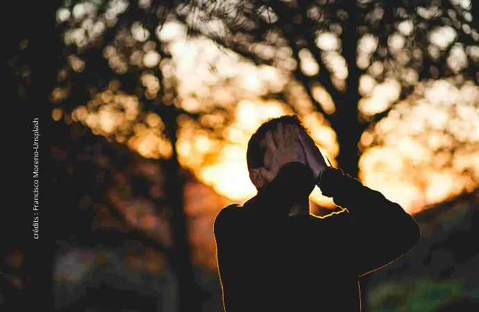 homme qui se tient la tête entre les mains dehors