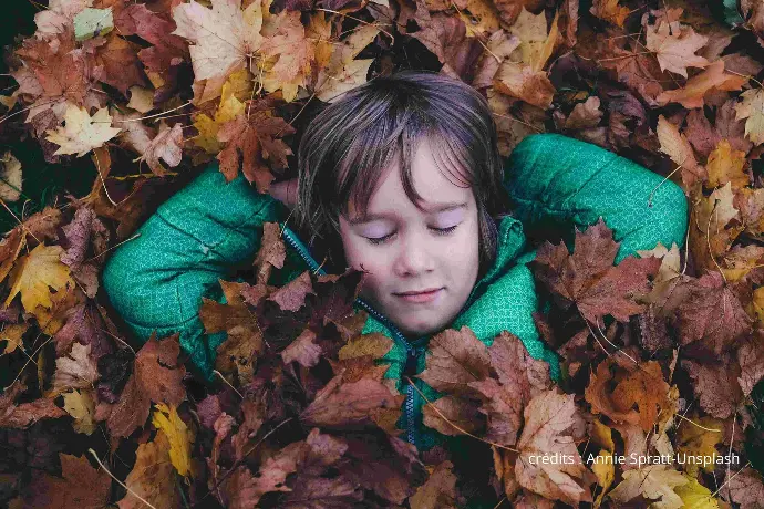 enfant allongé dasn les feuilles mortes